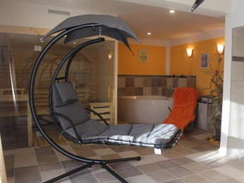 Sauna Moderne Wellnessoase mit Hängesessel, Whirlpool und Sauna in hell beleuchtetem Raum.