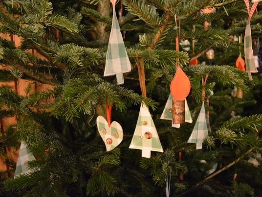 Stoffanhänger auf dem Weihnachtsmarkt Verschiedene handgefertigte Stoffanhänger schmücken einen Tannenbaum; darunter Herzen und Tannenbäume.