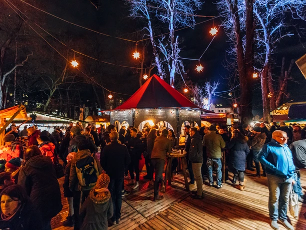 Weihnachtsmarkt am Felsenkeller - Weihnachten in Leipzig Blick auf den gut besuchten Weihnachtsmarkt am Felsenkeller am Abend, mit hell erleuchteten Sternen, die wie eine Lichterkette zwischen den Bäumen gespannt sind