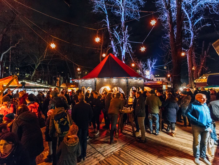 Weihnachtsmarkt am Felsenkeller - Weihnachten in Leipzig Blick auf den gut besuchten Weihnachtsmarkt am Felsenkeller am Abend, mit hell erleuchteten Sternen, die wie eine Lichterkette zwischen den Bäumen gespannt sind
