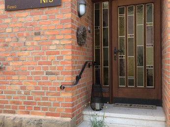 HofHausNr3 - Hauseingang Steintreppe mit Blumen führt zu einer Holztür mit dekorativem Glasfenster bei HofHaus Nr3.