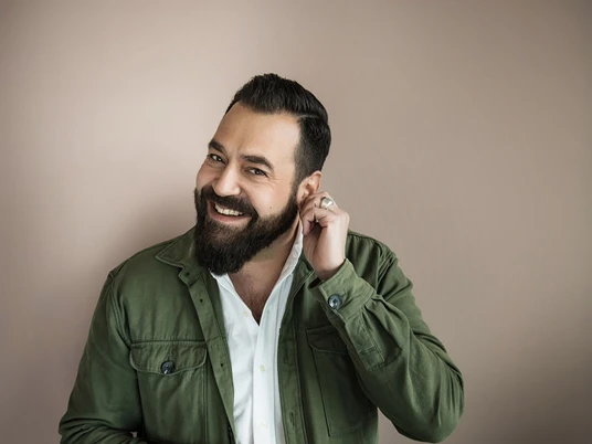 20230825_Laith_Al-Deen_(c)_Chris_Gonz.jpg Sänger Laith Al-Deen lächelt herzlich, trägt Jacke und Hemd, steht vor einem neutralen Hintergrund.