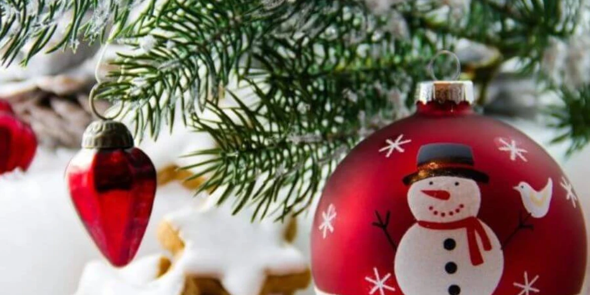 Weihnachtskugel.jpg Rot-weiße Weihnachtskugel mit Schneemann, hängend an Tanne, daneben rote Herzornamente und Kekse.Red and white Christmas bauble with a snowman hanging from a fir tree, with red heart ornaments and cookies next to it.Rød og hvid julekugle med en snemand, der hænger fra et grantræ, med røde hjerteornamenter og småkager ved siden af.Rode en witte kerstbal met een sneeuwpop hangend aan een dennenboom, met rode hartornamenten en koekjes ernaast.