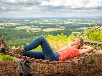 Frau liegt entspannt in der Hängematte mit Blick auf die hügelige Landschaft des Teutoburger Waldes.