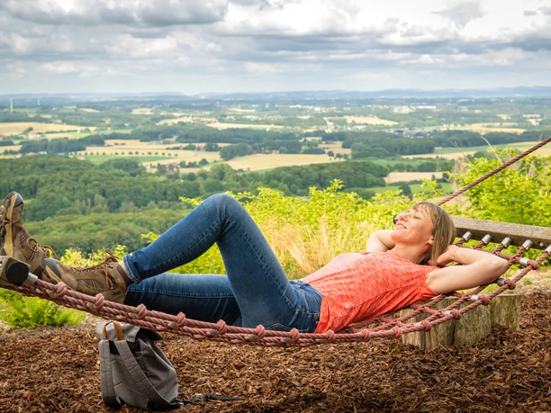 Frau liegt entspannt in der Hängematte mit Blick auf die hügelige Landschaft des Teutoburger Waldes.