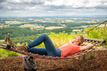 Werther-Hermannshöhen-Teutoburger-Wald-Tourismus-D-Ketz-087.jpg Frau liegt entspannt in der Hängematte mit Blick auf die hügelige Landschaft des Teutoburger Waldes.