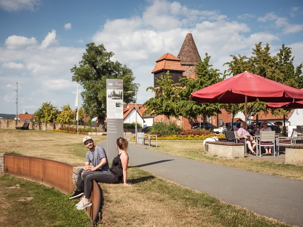 Café Ankerplatz im Emmerauenpark Menschen entspannen sich im Emmerauenpark, umgeben von Cafés und historischer Architektur.