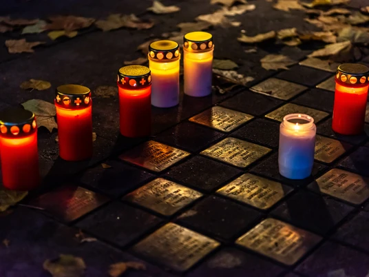 Musterbild Stolpersteine Stolpersteine mit Kerzenlicht umgeben, erinnern im Abendlicht an Holocaust-Opfer, umgeben von Laub.