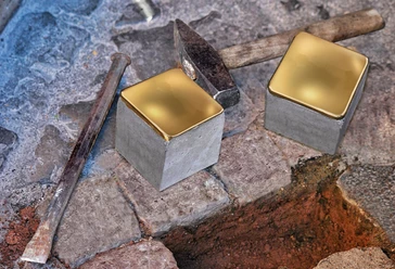 Zwei glänzende Stolpersteine aus Messing liegen auf einem historischen, gepflasterten Gehweg.
