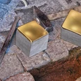 Musterbild Stolpersteine Zwei glänzende Stolpersteine aus Messing liegen auf einem historischen, gepflasterten Gehweg.