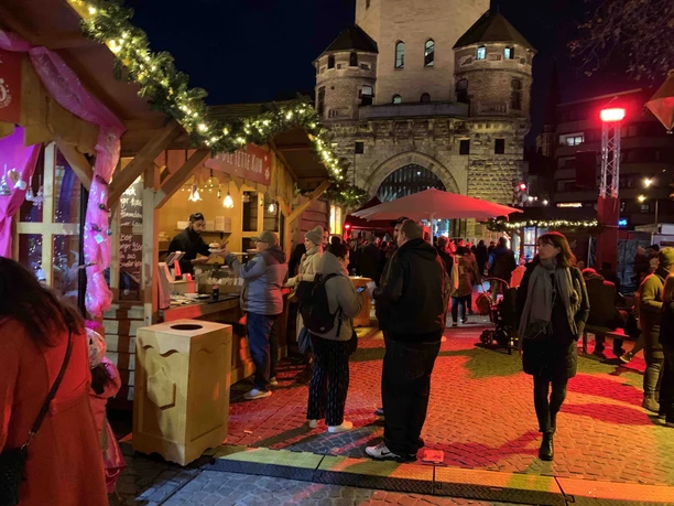 Vringsadvent - Weihnachtsmarkt auf dem Chlodwigplatz Belebter Weihnachtsmarkt mit Buden vor beleuchtetem Stadttor in nächtlicher Atmosphäre