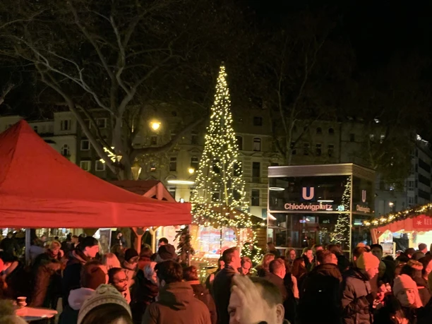 Vringsadvent - Weihnachtsmarkt auf dem Chlodwigplatz Menschen auf beleuchtetem Weihnachtsmarkt am Chlodwigplatz mit geschmücktem Baum