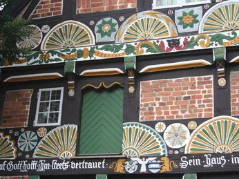 Half-timbered façade of a historic farmhouse in Verden, richly decorated with colorful carvings.