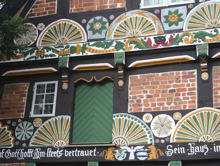 Ackerbürgerhaus Verden Fachwerkfassade eines historischen Ackerbürgerhauses in Verden, reich verziert mit buntem Schnitzwerk.Half-timbered façade of a historic farmhouse in Verden, richly decorated with colorful carvings.Bindingsværksfacade på en historisk gård i Verden, rigt udsmykket med farverige udskæringer.Vakwerkgevel van een historische boerderij in Verden, rijkelijk versierd met kleurrijk houtsnijwerk.
