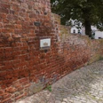 Rote Backsteinmauer aus dem Mittelalter in Verden, durchzogen von einem gepflasterten Weg.