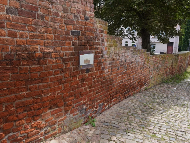 Rote Backsteinmauer aus dem Mittelalter in Verden, durchzogen von einem gepflasterten Weg.