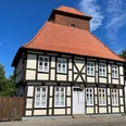 Alter Wehrturm Verden mit Scharfrichterhaus Fachwerkgebäude mit rotem Ziegeldach und gemauertem Turm in Verden unter klarem, blauem Himmel.