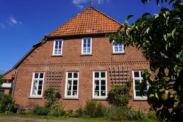 Dauelsen Alte Schule Backsteinfassade der Alten Schule in Dauelsen mit gepflegtem Garten, Fenster mit weißen Sprossen.