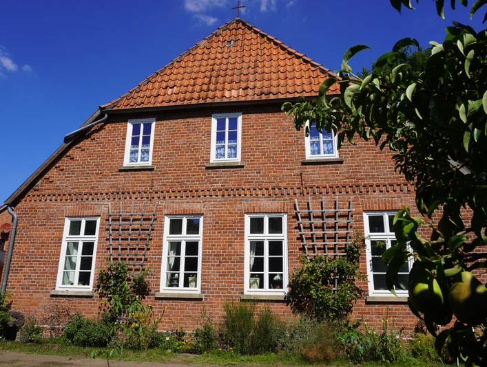 Dauelsen Alte Schule Backsteinfassade der Alten Schule in Dauelsen mit gepflegtem Garten, Fenster mit weißen Sprossen.