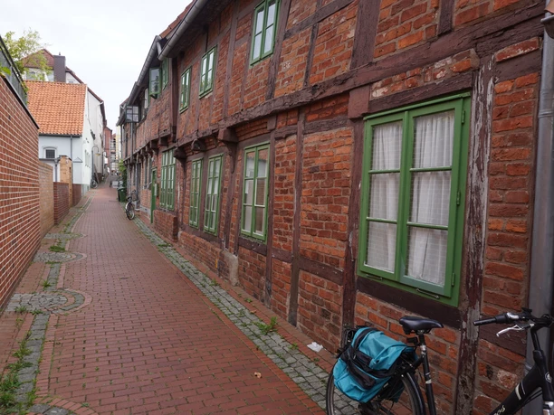 Half-timbered houses with green shutters line a narrow, cobblestone alley in Verden.