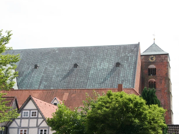 Historic brick church in Verden with a striking nave and red roof, surrounded by houses.