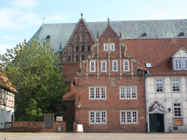Dom Verden Historischer Backsteinbau mit Staffelgiebel vor einer großen gotischen Kirche unter blauem Himmel.