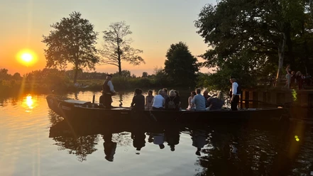 HammeNacht - Ein Abend auf der Hamme Een verlichte turfschuit vaart de haven van Hamme uit tegen de zonsondergang tijdens HammeNacht