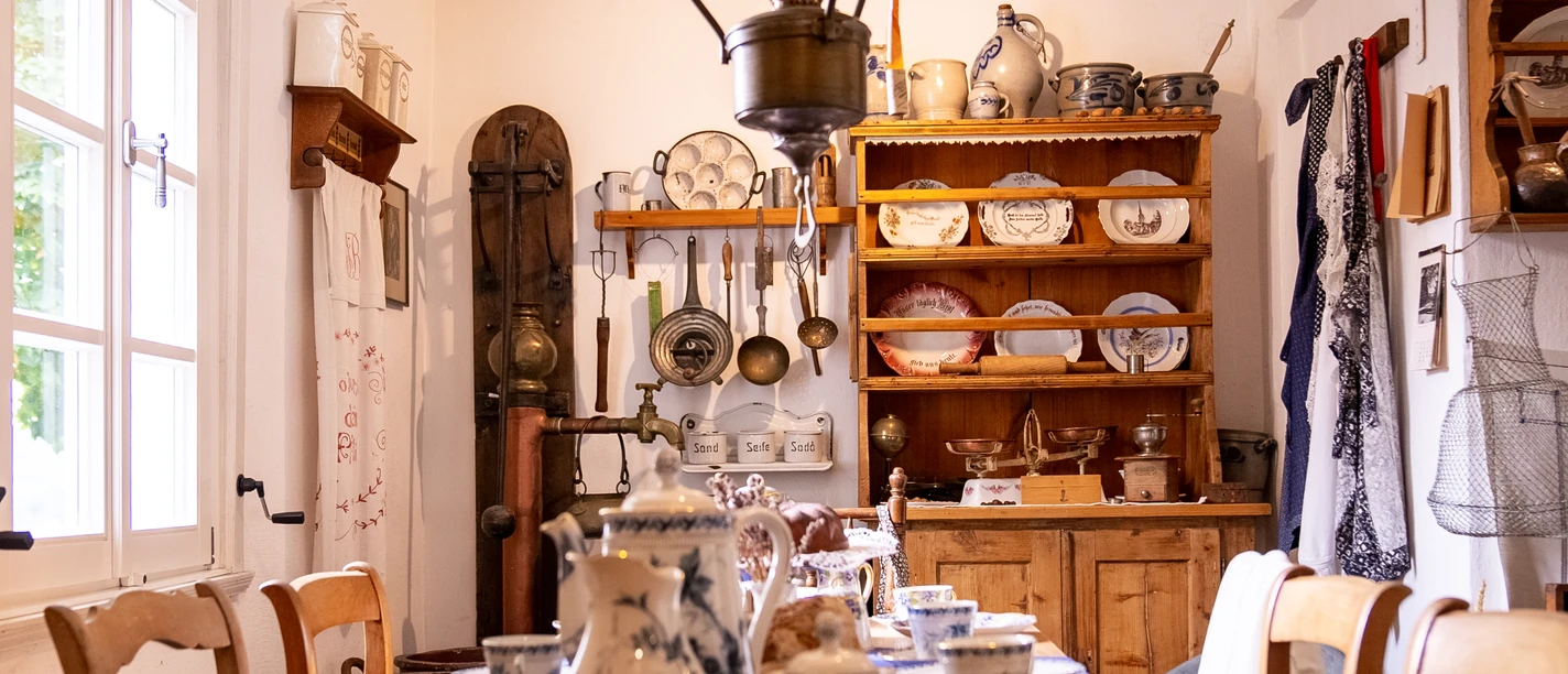 Alte Küche mit Geschirr, Töpfen, traditionellem Charme und blauen Dekorelementen im Landhausstil.