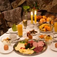 Hotel & Restaurant Klosterkrug - Frühstück Ein opulent gedeckter Frühstückstisch mit Wurst, Käse, Brot, Saft und Kerzenlicht.
