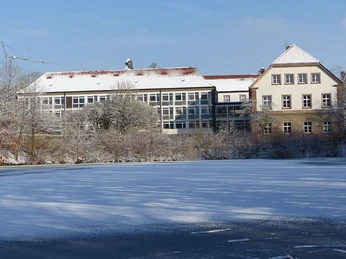 Landesvolkshochschule Hardehausen - Winter Schnee bedeckt das Gelände der Landesvolkshochschule Hardehausen vor einem klaren winterlichen Himmel.