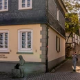 Altes Stadthaus Wipperfürth Ablasshäuschen in Wipperfürth mit traditioneller Architektur und einer Frau, die ein Mobiltelefon benutzt.