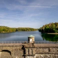 Neyetalsperre Die Lingese-Talsperre bei Wipperfürth mit einer Steinbrücke und Wäldern im herbstlichen Grün.