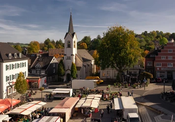 Marktplatz Wipperfürths idyllischer Marktplatz mit historischen Gebäuden und St. Nikolaus Kirche, Marktstände im Vordergrund.