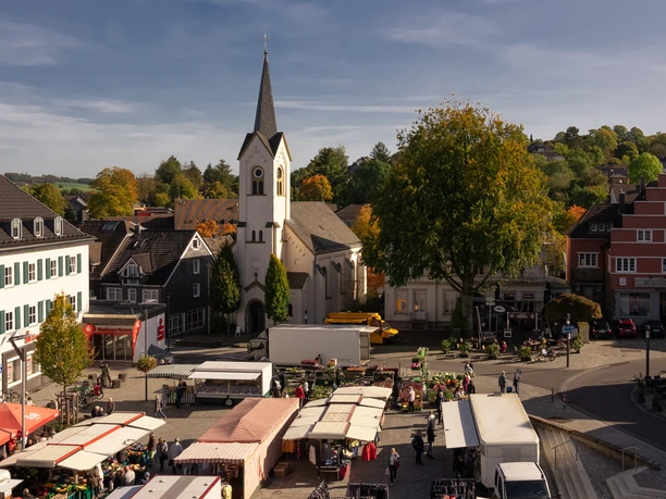 Marktplatz Wipperfürths idyllischer Marktplatz mit historischen Gebäuden und St. Nikolaus Kirche, Marktstände im Vordergrund.