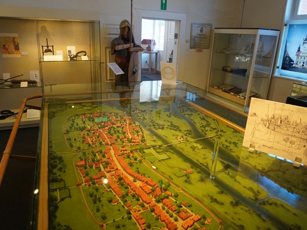 A detailed model of a settlement landscape is displayed in an exhibition room with showcases.