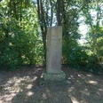 Bornemacher Stele Stele aus grauem Stein in Waldlichtung, umgeben von grünen Bäumen bei Tageslicht, steht ruhig.