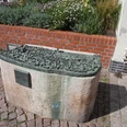 Detailliertes Bronzemodell der Altstadt Verden auf einem Steinsockel, umgeben von Blumenbeet.