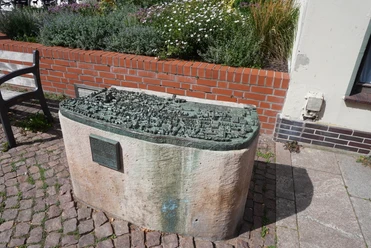 Stadtmodell Verden Detailliertes Bronzemodell der Altstadt Verden auf einem Steinsockel, umgeben von Blumenbeet.