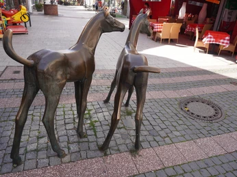 Bronzene Fohlen-Skulpturen stehen auf einem gepflasterten Platz in der Fußgängerzone von Verden.