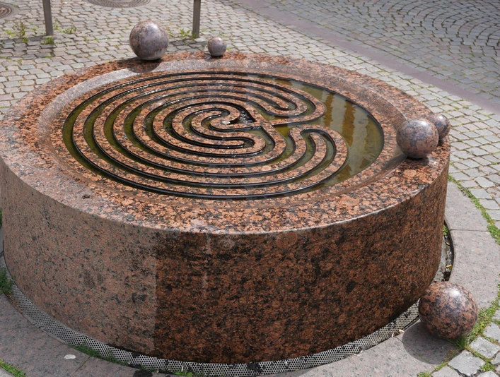 Der Gezeitenbrunnen in Verden ist ein runder, spiralförmiger Brunnen aus rötlichem Granit mit Kugeln.