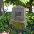 Lutherstein Gedenkstein von Büschen umgeben, mit Plakette darauf, in einem von Bäumen beschatteten Gebiet.