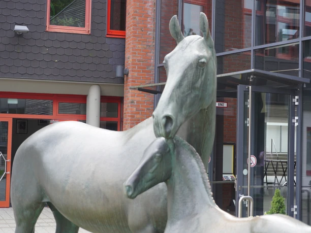 Statuen einer Mutterstute mit Fohlen aus Bronze vor einem modernen Gebäude in Verden.