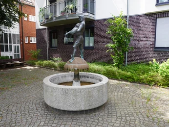 Störtebeker-Brunnen in einem Innenhof, zeigt eine Bronzestatue mit erhobenem Krug auf steinernem Brunnen.
