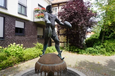 Störtebeker-Brunnen Brunnen mit einer Statue des Seeräubers Störtebeker in einer ruhigen Gartenanlage an einem gepflasterten Weg.