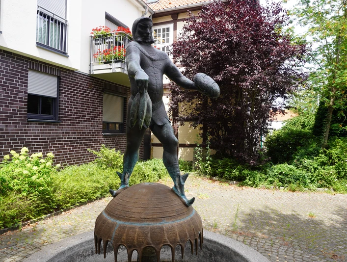 Störtebeker-Brunnen Brunnen mit einer Statue des Seeräubers Störtebeker in einer ruhigen Gartenanlage an einem gepflasterten Weg.
