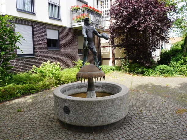 Störtebeker-Brunnen Bronzestatue eines historischen Seeräubers am Brunnen in gepflastertem Hof, flankiert von Gebäuden.