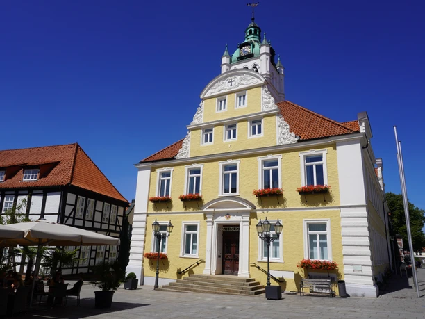 Historisch stadhuis van Verden met gele gevel, witte accenten en decoratieve bloembakken.
