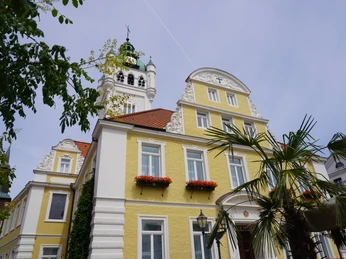 Historisches Rathausgebäude in Verden, gelblich mit weißen Verzierungen und bepflanzten Fenstern.