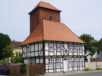 Alter Wehrturm Verden mit Scharfrichterhaus Historischer Fachwerkbau mit rotem Ziegeldach und Wehrturm in Verden, umgeben von grüner Umgebung.