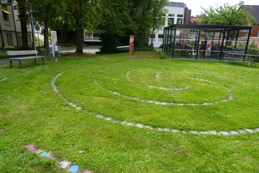 Spirallabyrinth Verden Spiralförmiges Labyrinth auf einer grünen Wiese, umgeben von Schildern und Bäumen in Verden.